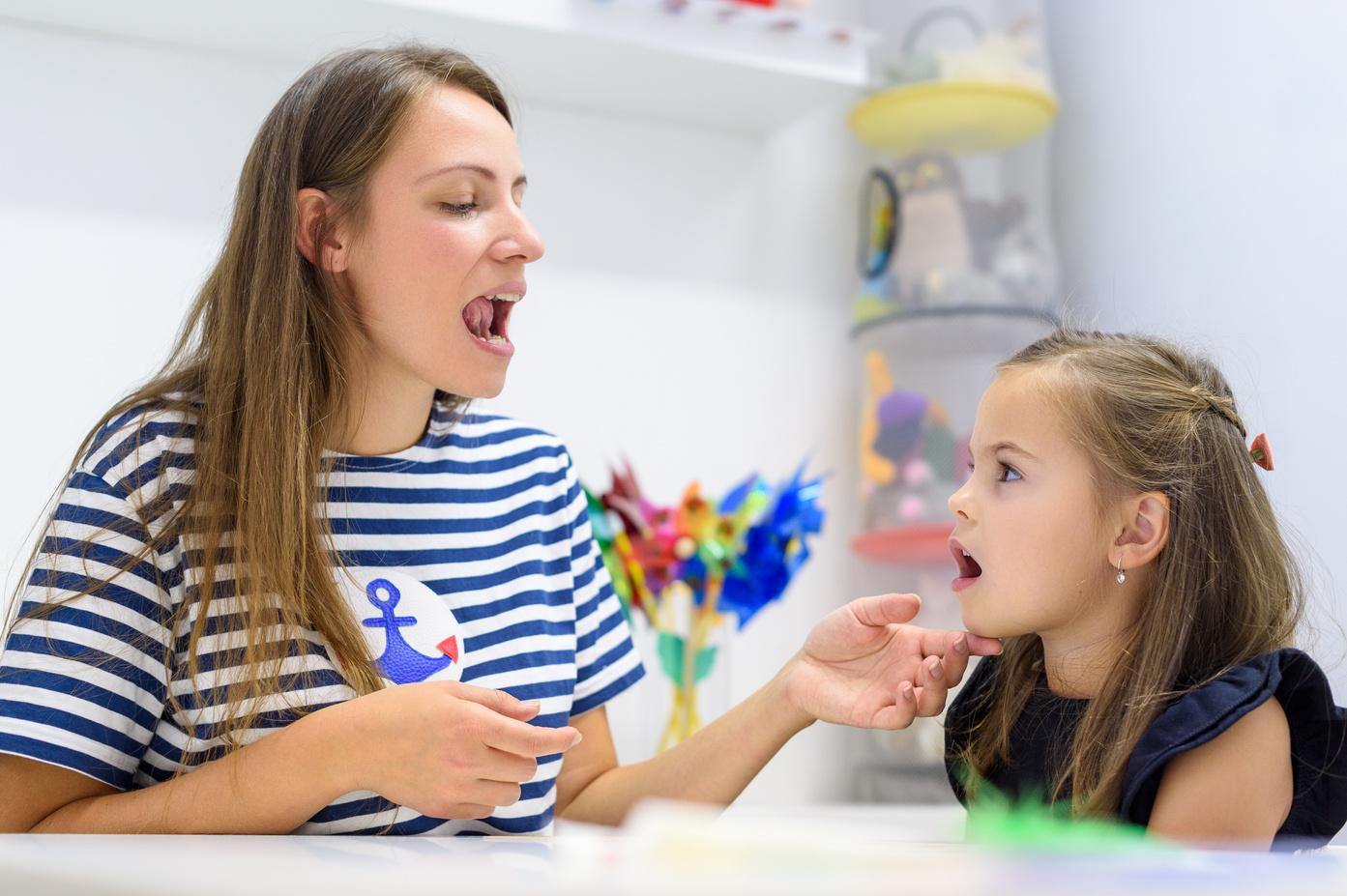 child and speech therapist, working on pronunciation together at a table